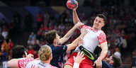 Handballspieler hoch in der Luft, um über die Gegenspieler den Ball ins Tor zu werfen