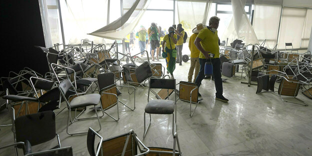 People break into a building, chairs lie in a jumble on the floor