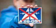 Jemand hält eine Karte mit dem durchgestrichenen Symbol für die A26 Ost in die Kamera