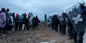 Polizisten und Demonstranten stehen sich bei der Demonstration von Klimaaktivisten am Rande des Braunkohletagebaus bei Lützerath gegenüber