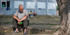 Ein Mann sitzt auf der Erde auf dem Gelände einer Erstaufnahmeeinrichtung in Eisenhüttenstadt