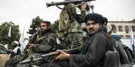 Taliban sitzen mit Waffen auf einem Jeep