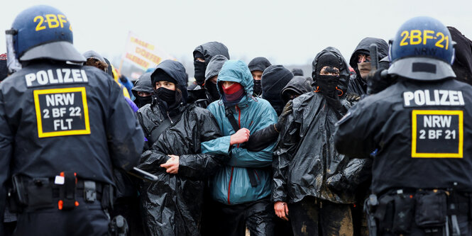 Das Bild zeigt den Polizeieinsatz am Braunkohletagebau in Lützerath vor den Demonstranten.