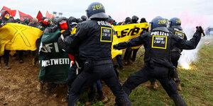 Polizisten sprayen mit Pfefferspray auf eine Reihe Klimademonstrant*innen
