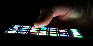 Smartphone-Display mit Daumen vor dunklem Hintergrund