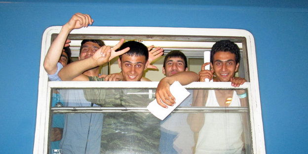 Fünf serbische Flüchtlinge schauen aus einem Zugfenster.