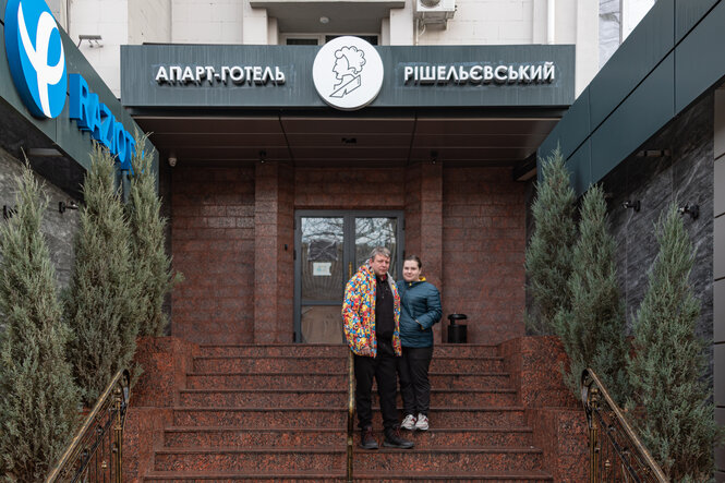 Ein Mann u nd eine Frau stehen vor einem Gebäude auf der Eingangstreppe