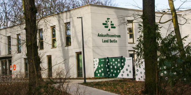 Das Ankunftszentrum für Gelüchtete in Berlin-Reinickendorf von außen - ein schmuckloser zweistöckiger Bau mit Nadelbäumen davor