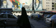 Frau im Tschador vor Portraits des Ayatollah Khomeini in Teheran