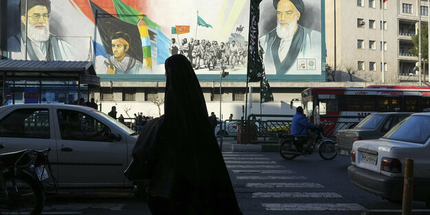 Woman in chador in front of portraits of Ayatollah Khomeini in Tehran