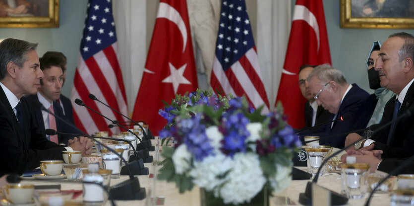 Blinken und cavusoglu sitzen zusammen am Tisch mit Fahnen im Hintergrund