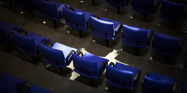 An empty row of chairs in the Bundestag is illuminated by sunlight
