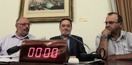 Panagiotis Lafazanis sitzt am Tisch hinter einer Uhr.