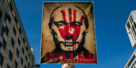 Ein Plakat mit dem Gesicht Putins auf dem eine rote (blut-verschmierte) Hand über dem Gesicht prangt und das Wort: Killer