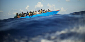 Viele Personen auf einem Holzboot im Meer