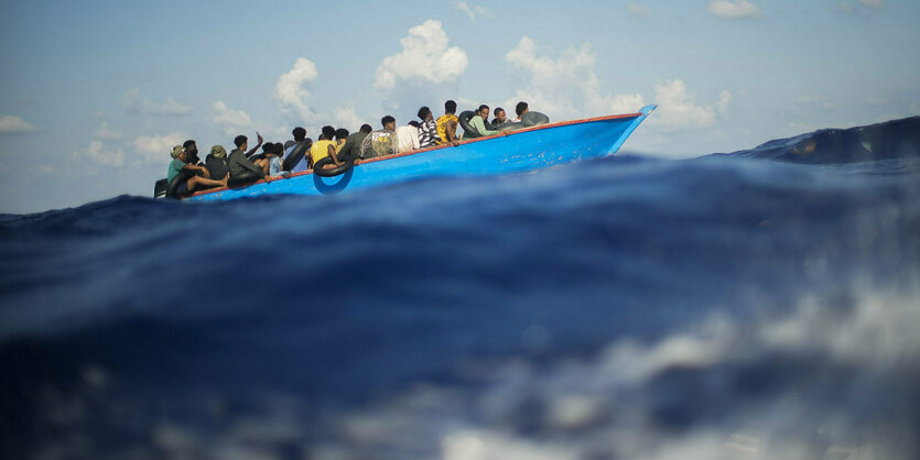 Viele Personen auf einem Holzboot im Meer