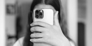 Einr Person hinter einem Smartphone versteckt