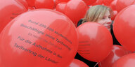 Das Gesicht der Frau ist zwischen vielen Luftballons zu sehen, auf die die Forderung nach einem Tarifvertrag aufgedruckt ist