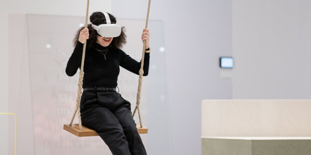 Eine Frau mit Virtuell Reality Brille sitzt auf einer Schaukel