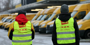 Zwei Streikende stehen vor stillstehenden Postautos