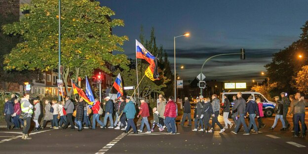 Demonstranten gehen mit russischen Flaggen und "Wir sind das Volk" Deutschlandfahnen über die Straßen