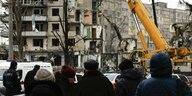 Eine Gruppe von Menschen steht vor einem zerstörten Gebäude in Dnipro