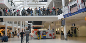 Menschen mit Gepäck stehen Schlange am Bremer Flughafen