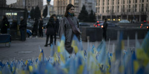 Eine Frau läuft an gelb-blauen Flaggen entlang