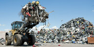 Ein Bagger transportiert Elektroschrott auf einem Recyclinghof
