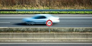 Temp 120 Schild amRand einer Autobahn, im Hintergrund ein Auto in Bewegungsunschärfe