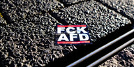 Ein "FCK AFD" Aufkleber liegt auf der Straße