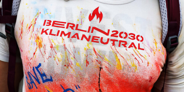 Ein Mann trägt ein buntes T-Shirt mit dem Aufdruck "Berlin 2030 klimaneutral" - ein Bild zum Interview mit einem Aktivisten der Kleinpartei Klimakiste