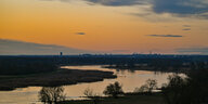 Ein Sonnenaufgang in orange und blau über dem Fluss Oder an der Grenze zu Polen. Im Hintergrund ist die Stadt Frankfurt (Oder) zu sehen.