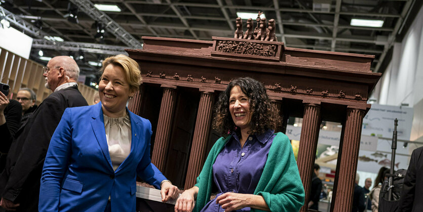 Franziska Giffey (SPD, l), Regierende Bürgermeisterin von Berlin, und Bettina Jarasch (Bündnis90/Die Grünen), Spitzenkandidatin für die Wahl des Berliner Abgeordnetenhaus, stehen auf dem Eröffnungsrundgang zur Internationalen Grünen Woche 2023 in der Berlin-Halle vor einem Schokoladen-Modell des Brandenburger Tors.