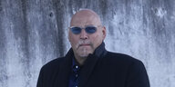 Oberkörper eines Mannes im Mantel mit blau getönter Sonnenbrille