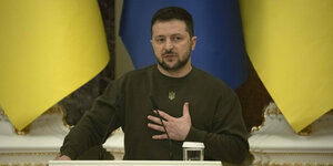 Ein Mann steht vor ukrainischen fahnen am Mikrofon