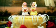 Zwei weibliche Figuren im Brautkleid stehen auf einer Torte