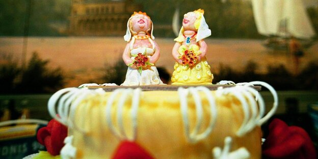 Zwei weibliche Figuren im Brautkleid stehen auf einer Torte