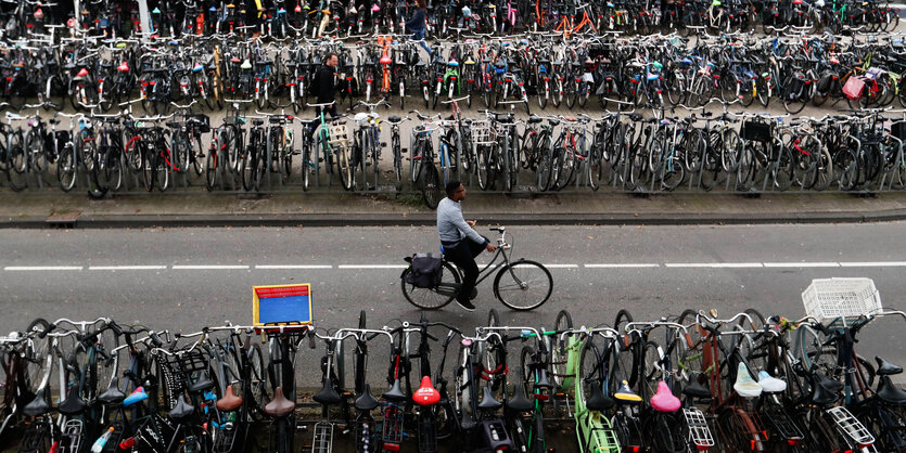 Das Bild zeigt einen Fahrradfahren - inmitten von abgestellten Rädern.