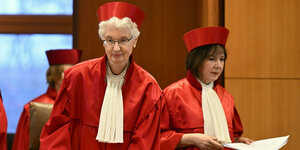 Doris König und Sibylle Kessal-Wulf stehen in roter Robe mit roter Kopfbdeckung im Bundesverfassungsgericht