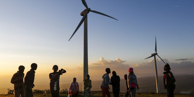 Windräder und Menschen vor Sonnenuntergang