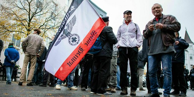Demonstranten von: "Die Rechte NRW" halten am Hauptbahnhof ein Fahne hoch - Reichskriegsflagge mit Adler und der Schirft: Meine Heimat