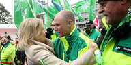Nancy Faeser umarmt einen Polizisten in grell-grünem Anorak, der mit seinen Kollegen von der Gewerkschaft vor dem Kongreßhotel steht