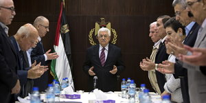 PLO-Komitee-Mitglieder bei Koranlektüre stehend am Konferenztisch.