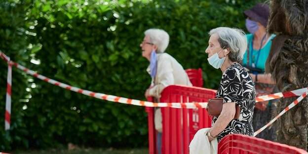 Bewohnerinnen eines Altersheims sprechen mit Mundschutz in sicherem Abstand mit ihren Familienangehörigen