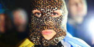 Eine Frau trägt eine leopardierte Maske und eine Ukrainische Fahne