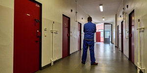 Ein Mann in blauer Häftlingskleidung auf einem Gefängnisflur
