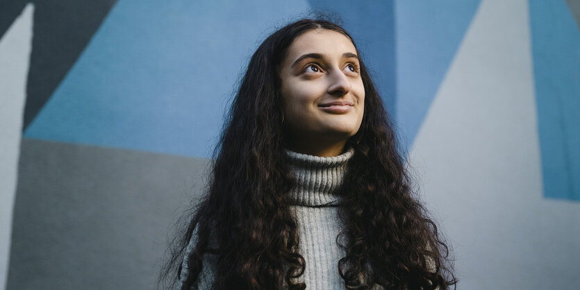 Portrait der Schulsprecherin Aylin Ünveren vor der gestalteten Brandwand des taz-Neubaus