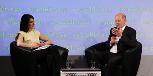 Moderatorin Linda Zervakis und Bundeskanzler Olaf Scholz sitzen auf schwarzeln Sesseln auf einer Bühne der Republica-Konferenz