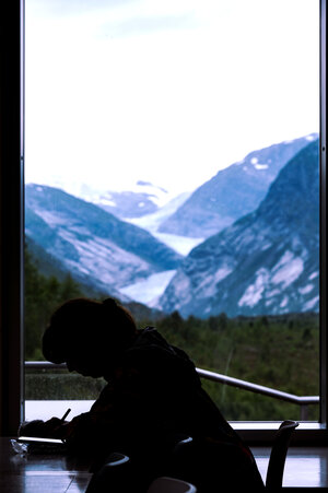 Silhouette der Autorin, die gerade schreibt vor dem Bergpanorama Silhouette der Autorin, die gerade schreibt vor dem Bergpanorama